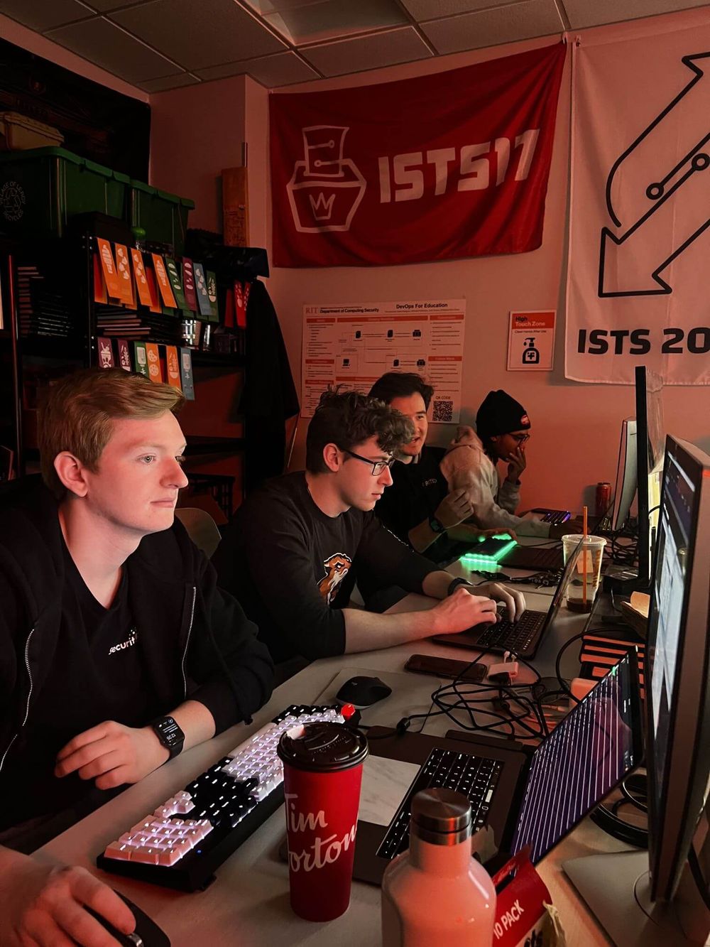 RITSEC working in the club room, with ISTS flags in the background.